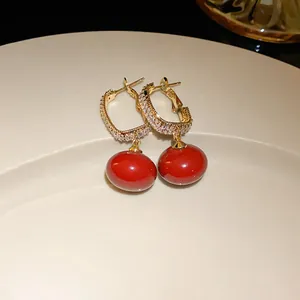 Detailed macro view of elegant gold-plated earrings with red drop beads and crystals