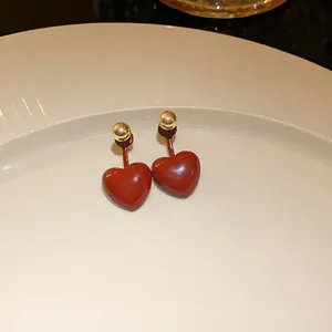 Detailed close-up of elegant red heart-shaped stud earrings with polished gold beads