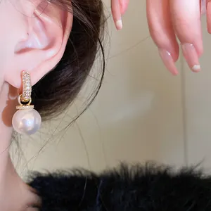 Elegant close-up of gold-plated zircon pearl drop earrings worn on a female ear