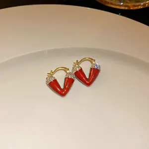 Macro shot of elegant red enamel V-shaped hoop earrings with crystal accents on a plate