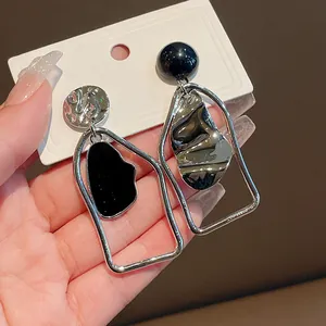 Dettaglio di orecchini smaltati asimmetrici geometrici con montatura rettangolare argento