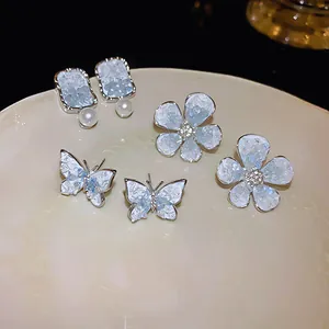 Set of elegant crystal flower and butterfly stud earrings with silver needles on a plate
