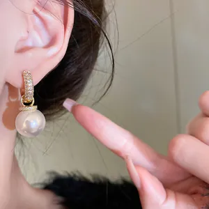 Detailed view of elegant gold-plated zirconia hoop earring with a large pearl pendant