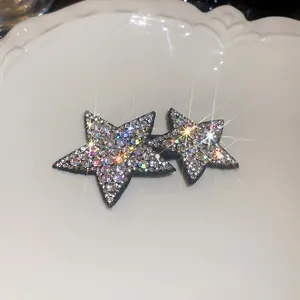 Close-up of sparkling Y2K star hair clips with iridescent rhinestones on white tray