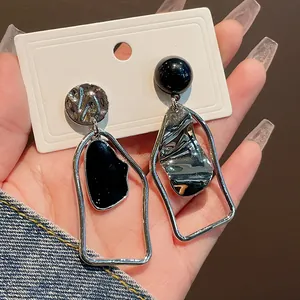 Dettaglio di orecchini geometrici asimmetrici con smalto nero e finitura color argento.