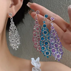 Primo piano di orecchini pendenti con strass colorati in argento, rosa, blu e viola.