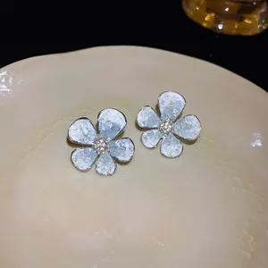 Close-up detail of elegant white flower-shaped stud earrings with crystal textured petals