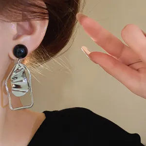 Primo piano di orecchini geometrici irregolari in argento con perni in smalto nero eleganti