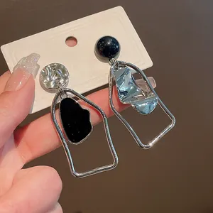Dettaglio di orecchini geometrici asimmetrici con smalto nero e finitura argento