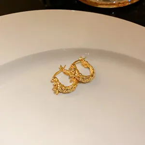 Detailed view of gold-plated textured hoop earrings with sparkling stones on a white plate