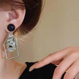 Dettaglio dell'orecchino geometrico irregolare in argento con perno nero sull'orecchio