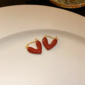 Close-up of elegant red heart hoop earrings with gold-plated finish on a white plate