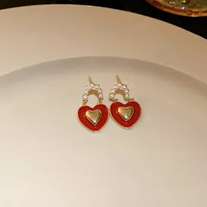 Detailed macro view of red heart earrings with gold plating and white pearl beads