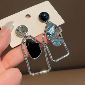 Dettaglio di orecchini geometrici asimmetrici color argento con smalto nero