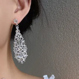 Primo piano di orecchini pendenti in argento con brillanti zirconi a forma di rombo