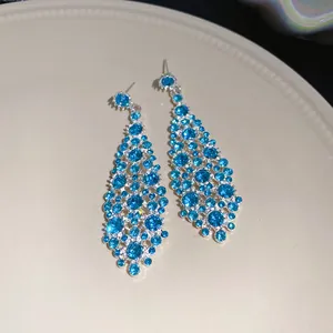 Primo piano di eleganti orecchini pendenti in strass blu con design a rombi irregolari.