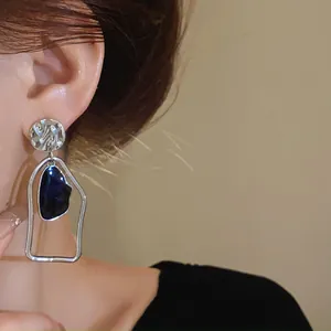 Primo piano di orecchini geometrici color argento con inserto in smalto blu scuro