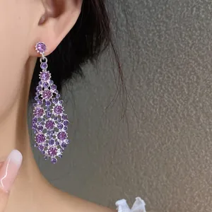 Dettaglio di eleganti orecchini pendenti in zircone viola con forma a rombo irregolare.