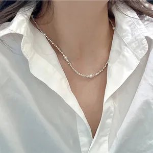 Detailed view of an elegant pearl and silver bead necklace worn with a white shirt