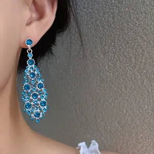 Vista dettagliata di eleganti orecchini a goccia in argento con zirconi blu a rombo.