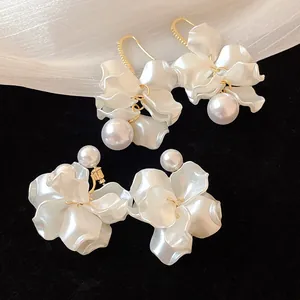 Macro detail of elegant 18K gold-plated pearl flower earrings on velvet background