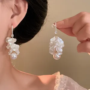 Close-up of 18K gold plated pearl tassel earrings with delicate white flower petals.