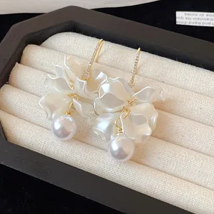 Elegant detail showing white flower petal earrings with round pearls in a cream box