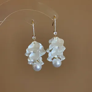 Macro detail of white flower petal earrings with hanging pearls and crystal studs