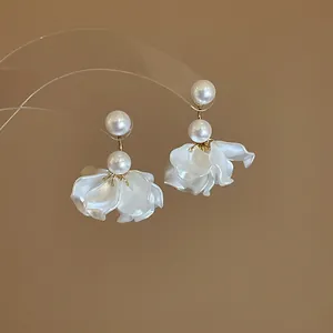 Macro view of elegant white pearl earrings featuring delicate flower petal tassels.