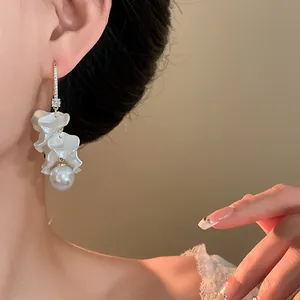 Detailed view of elegant white petal tassel earrings with a pearl on a model's ear.