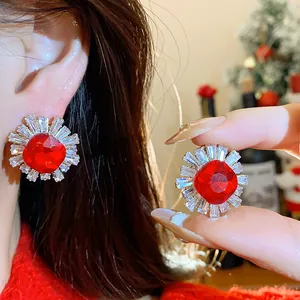 Close-up view of sparkling red zircon stud earrings in vintage palace style on an ear.