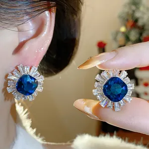 Close-up of blue square zircon stud earrings with sparkling starburst zircon halo