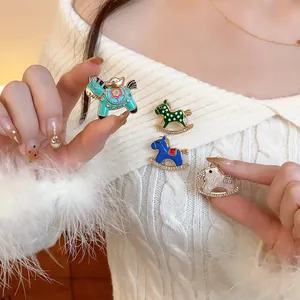 Close-up of colorful enamel rocking horse brooches pinned on white sweater