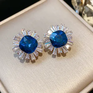 Macro detail of vintage palace style stud earrings featuring deep blue and clear zircons