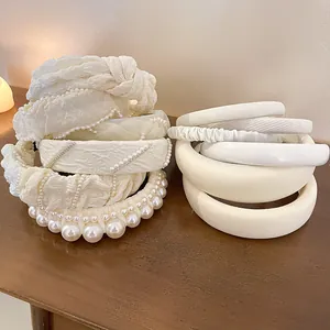 Sortiment eleganter weißer Perlen- und Gaze-Haarbänder für Damen auf einem Holztisch