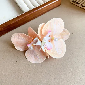 Elegant fabric orchid hair clip with pearl center, featuring delicate peach petals.