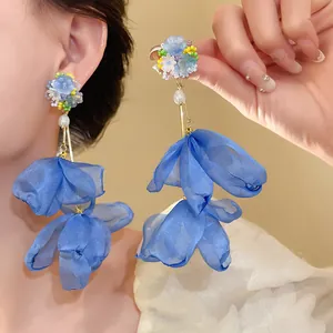 Close-up of elegant blue chiffon flower tassel earrings with pearls and beads on ear