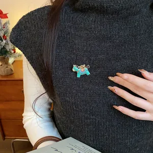 Close-up view of a turquoise enamel horse brooch pinned on a black knitted vest
