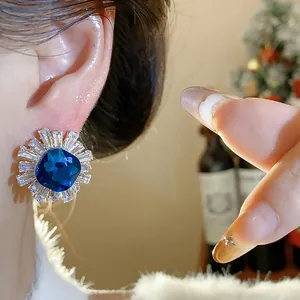 Detailed macro view of vintage palace style blue zircon stud earrings on model's ear