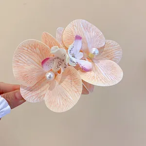 Close-up detail of elegant peach fabric orchid hair clip with pearl accents for women