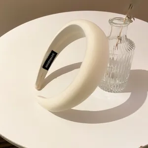 Detailansicht eines eleganten weißen gepolsterten Stirnbands mit handgemachtem Etikett