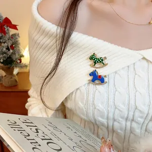 Detailed view of two cute rocking horse brooches with rhinestones on a white sweater