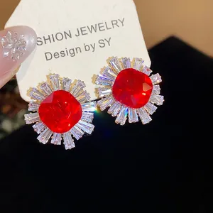 Close-up of vintage palace-style earrings with red square zircon and clear sunburst halo