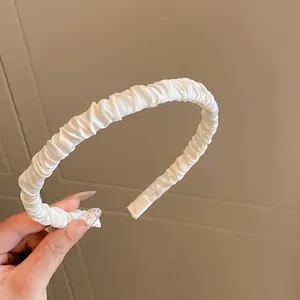 Nahaufnahme eines weißen, gerafften Satin-Haarreifs mit elegantem Volumen und Textur