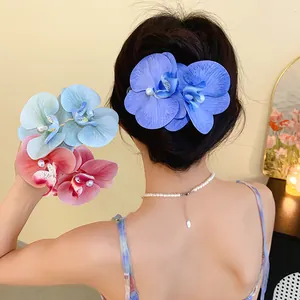 Macro view of blue fabric orchid hair clips with pearls worn by an elegant woman