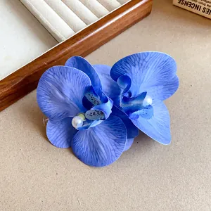 Close-up of blue fabric orchid hair clip with pearl detail for beach vacation style