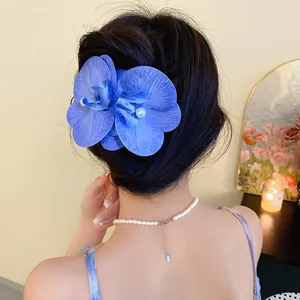 Detailed view of elegant blue fabric orchid hair clip with pearl accents on model