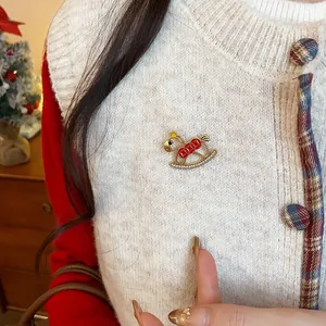 Close-up of a gold rocking horse brooch with red enamel and sparkling rhinestones.