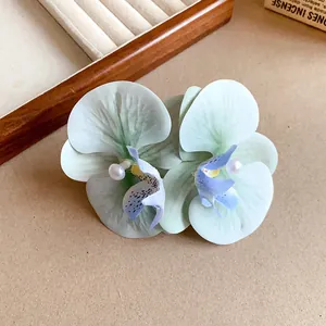 Close-up of elegant fabric orchid hair clips with pearls and delicate purple petal details