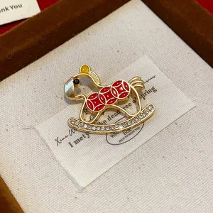 Detailed close-up view of rocking horse brooch with red enamel coins and rhinestones